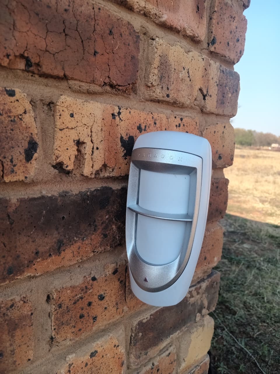 Paradox outdoor motion detector on the corner of a brick house, facing open veld